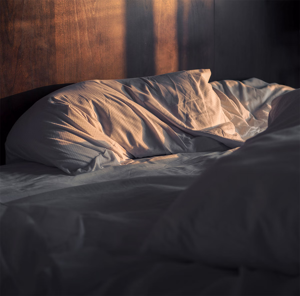 Cama sin hacer con luz de atardecer